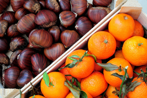 high angle view chestnuts and tangerine in a box, winter fruit on a market