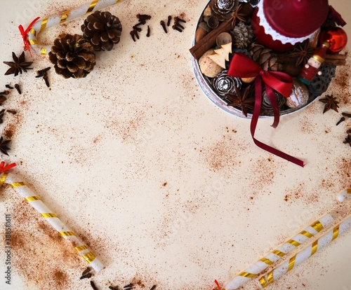Christmas card: box with a red candle surrounded by pine cones, cinnamon, star anise and walnuts surrounded by cinnamon powder, candy canes, star anise and cloves