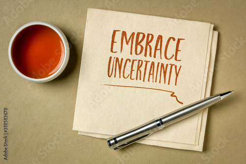 embrace uncertainty motivational note - handwriting on a napkin with a cup of tea, unknown future, change, risk and chance concept photo