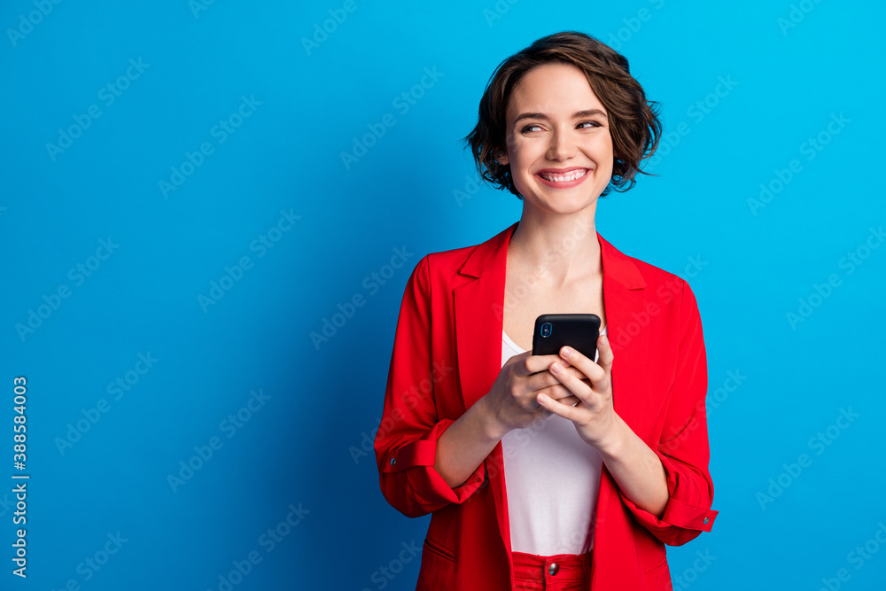 Naklejka premium Portrait of attractive glad cheerful brown-haired lady using gadget looking aside copy space isolated over bright blue color background