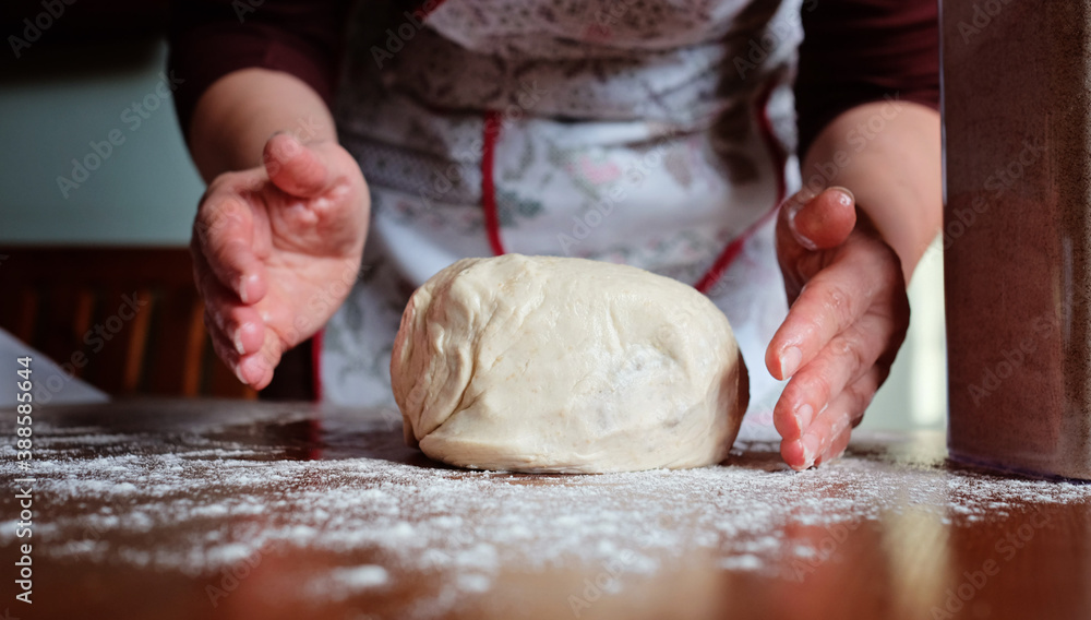 Senior woman hands knead dough on a table in her home kitchen Senior woman hands knead dough on a table in her home kitchen