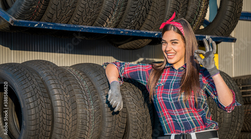 A female mechanic portrait in a front of winter tires on the shelf