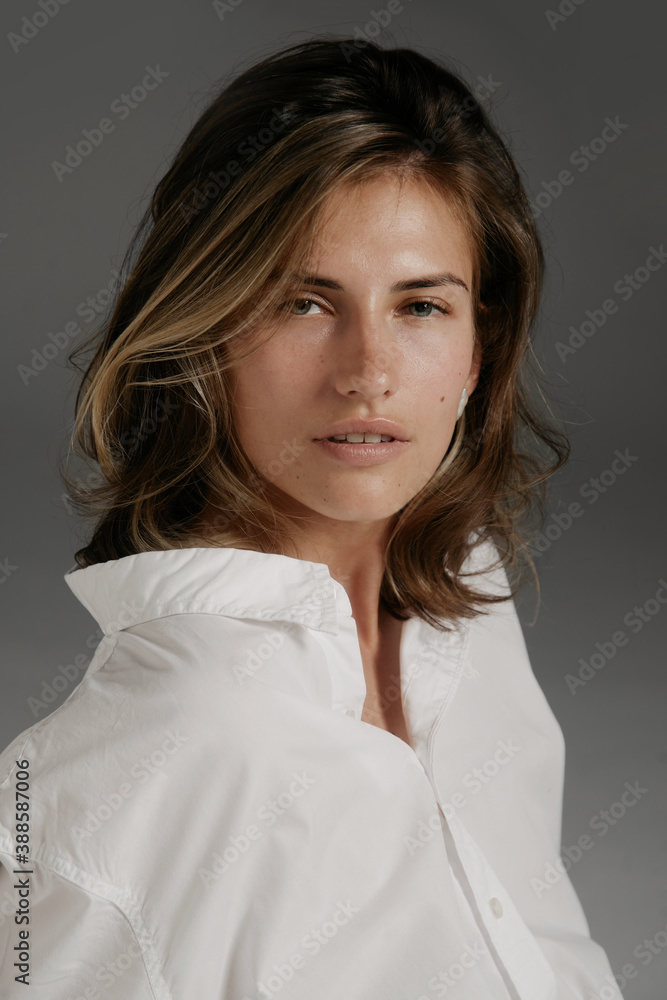 Portrait of beautiful young woman with brown hair and clean skin without makeup on grey background. Natural and healthy look. Soft light. Portrait of beautiful young woman with brown hair and clean skin without makeup on grey background. Natural and healthy look. Soft light.