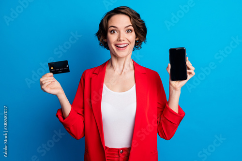 Portrait of attractive amazed cheerful lady demonstrating device card wireless web app pay pass transfer isolated on bright blue color background
