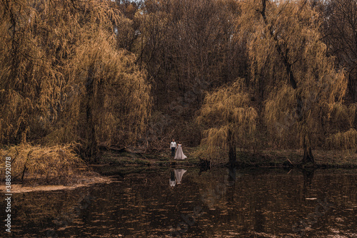 married couple a man with a pregnant woman with a big belly stand on a wooden bridge on coast lake river in nature. Aerial drone top view