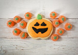 Top down view of a Halloween Jack o'lantern cookie and pumpkin shaped candies.