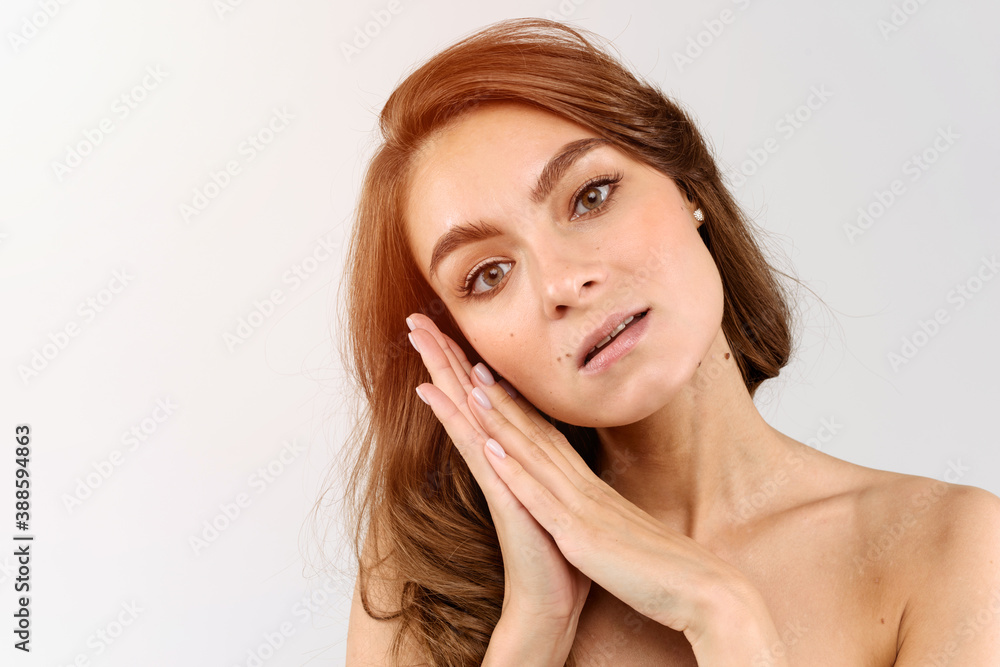 Beautiful young woman's face with healthy perfect clean skin, hands near cheek. Spa facial treatment skincare health concept. Isolated over white background Beautiful young woman's face with healthy perfect clean skin, hands near cheek. Spa facial treatment skincare health concept. Isolated over white background