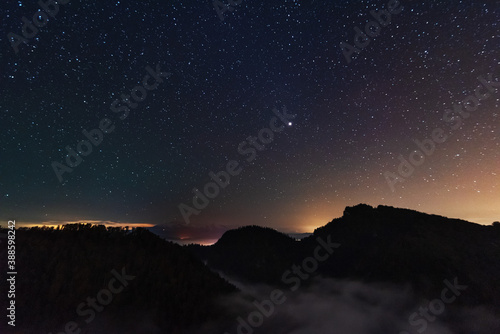 A beautiful starry night in the mountains on top with beautiful scenery and fog.