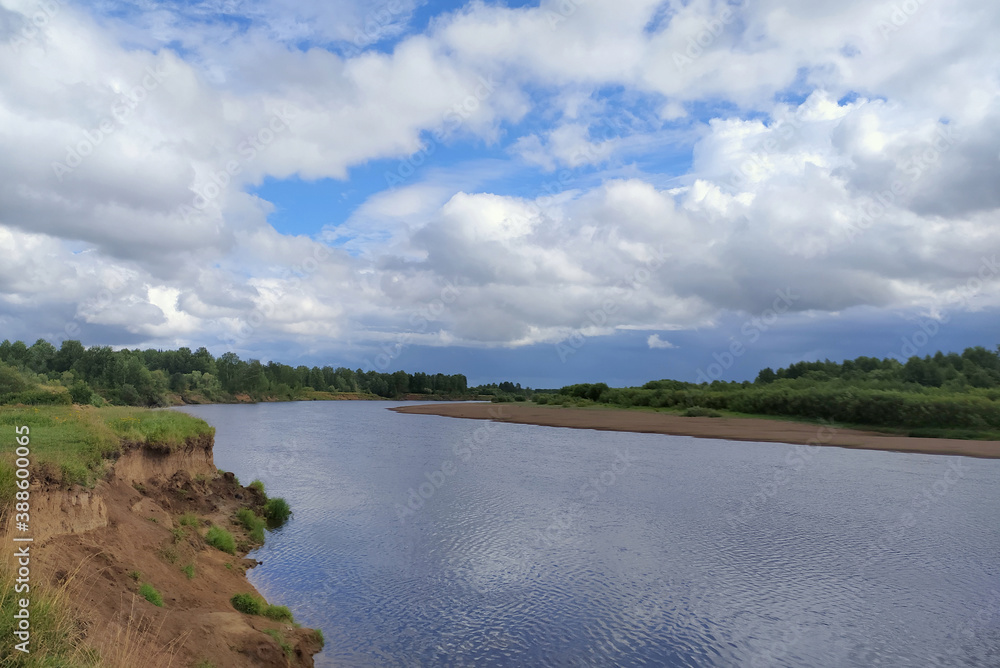 Landscape overlooking the river, sandy beach and green vegetation. A lake in Russia in summer with a coastline and trees. Blue sky with white clouds Landscape overlooking the river, sandy beach and green vegetation. A lake in Russia in summer with a coastline and trees. Blue sky with white clouds
