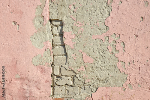 old brick wall with fragments of plaster and pink paint