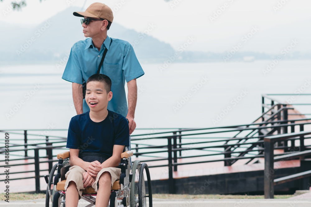 Disabled child on wheelchair is smiling,playing with father in outdoors park activity like other people,Lifestyle of special child, Life in the education age of children, Happy disability kid concept.