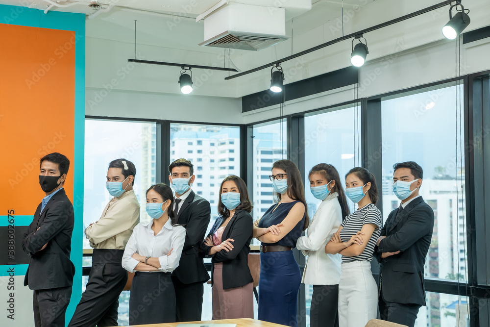 Diverse business people group with face mask protect from Corona virus standing together as team in office,Support and collaboration together to overcome pandemic of Corona virus to reopen business. Diverse business people group with face mask protect from Corona virus standing together as team in office,Support and collaboration together to overcome pandemic of Corona virus to reopen business.