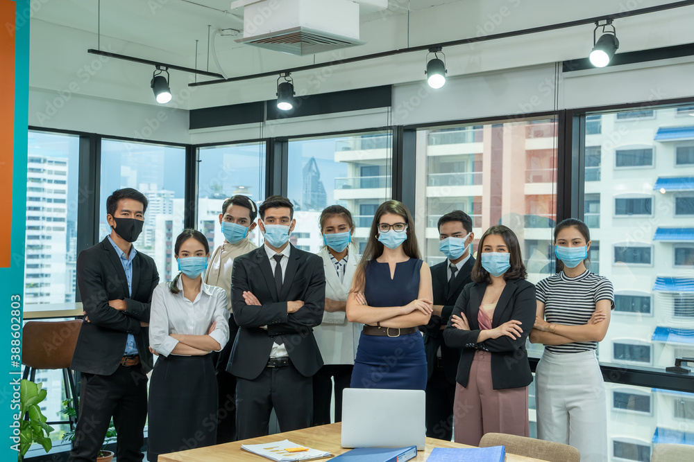 Diverse business people group with face mask protect from Corona virus standing together as team in office,Support and collaboration together to overcome pandemic of Corona virus to reopen business. Diverse business people group with face mask protect from Corona virus standing together as team in office,Support and collaboration together to overcome pandemic of Corona virus to reopen business.