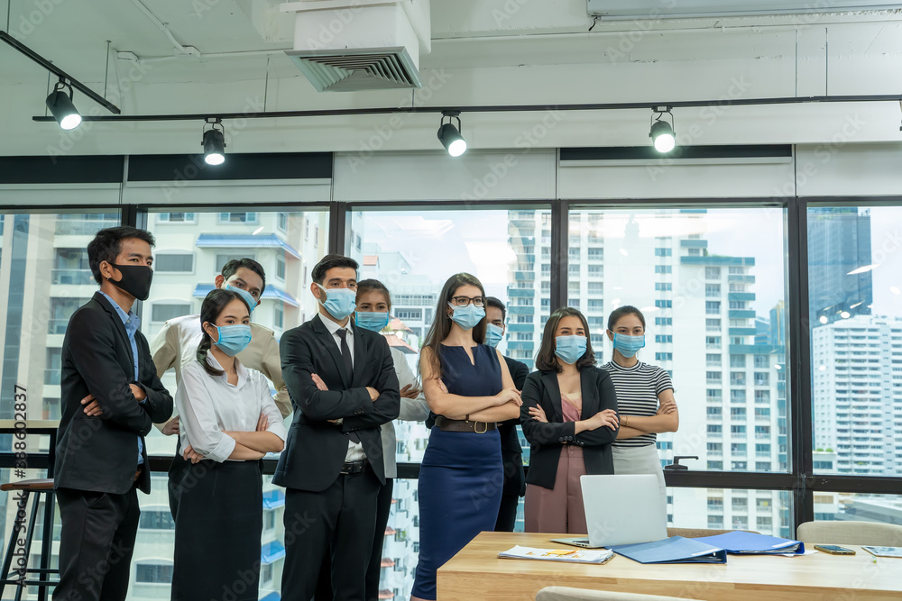 Diverse business people group with face mask protect from Corona virus standing together as team in office,Support and collaboration together to overcome pandemic of Corona virus to reopen business. Diverse business people group with face mask protect from Corona virus standing together as team in office,Support and collaboration together to overcome pandemic of Corona virus to reopen business.