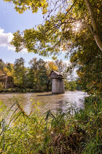 Wooden cottage on abandoned bridge pillar in autumn sunny day photo