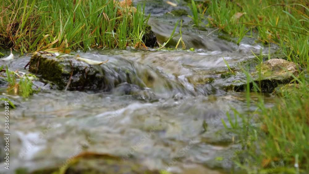 Pure fresh water, a stream with clear water flows from the mountain to the lake Pure fresh water, a stream with clear water flows from the mountain to the lake