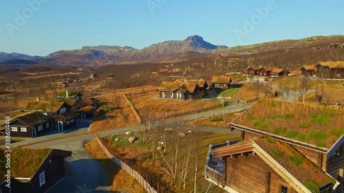 Luxury mountain cabins with grass turf roof in autumn colors at Beitostølen national park. 4K Aerial fly around video,