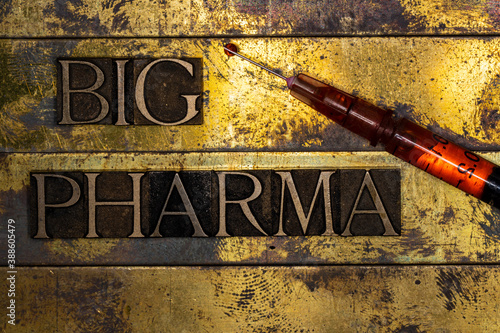 Big Pharma text message with drop of red fluid on tip of syringe on vintage textured gold background photo