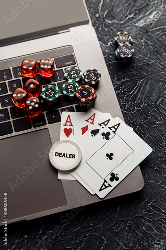 Chips, red dices and playing cards on laptop for poker online or casino gambling close-up. Online casino theme. photo