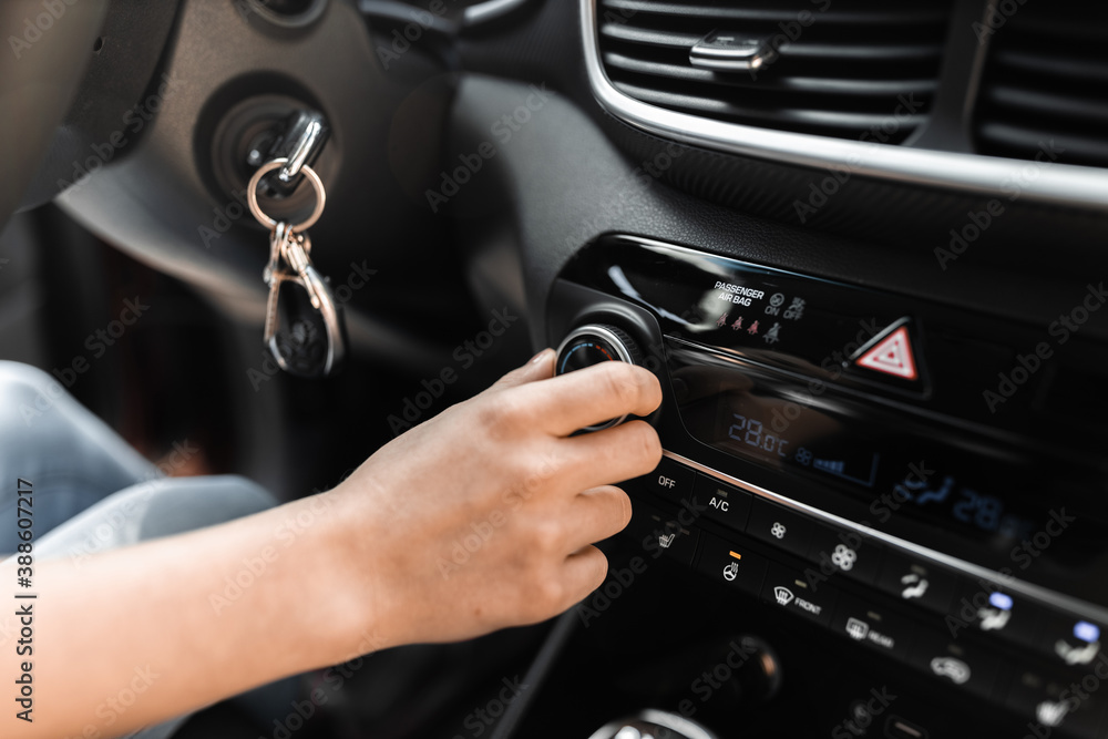 Interior view of a modern new car. Woman's hand and climatronic or air conditioner system concept. Interior view of a modern new car. Woman's hand and climatronic or air conditioner system concept.