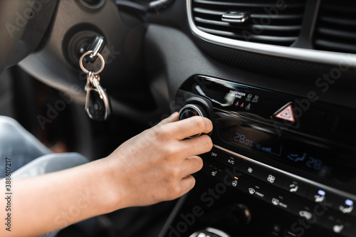 Interior view of a modern new car. Woman's hand and climatronic or air conditioner system concept. photo