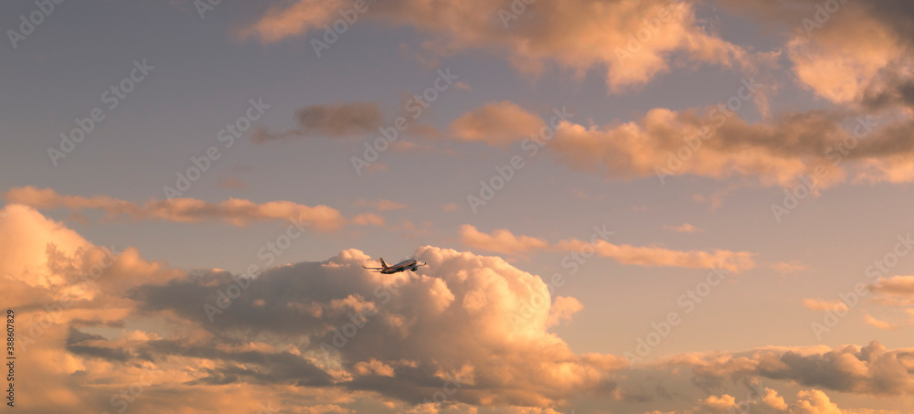 Fototapeta premium Flying airplane with bright big clouds in sunset colors