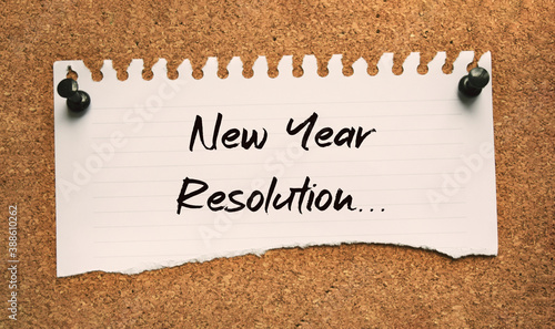 Paper note written with NEW YEAR RESOLUTION inscription on cork board