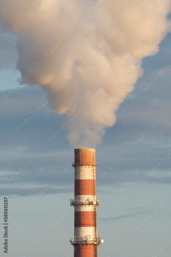 Factory smokestack against the blue sky. White smoke close up