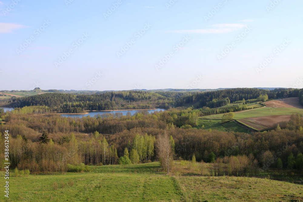 The panorama of the Suwalki Region. Suwalki Region, Poland. View of green meadows, hills, trees and the lake