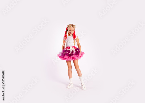 Wallpaper Mural portrait of a cute girl in bright multicolored clothes and with colored braids and in a skirt shows dance exercises on a white background Torontodigital.ca