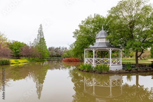 A white pagoda surrounded by trees on a garden pond