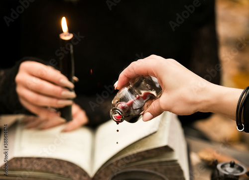 Fototapet The witch conducts a ritual, drips wine on the witchcraft book