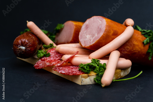 Different ham and salami with herbs on a dark background