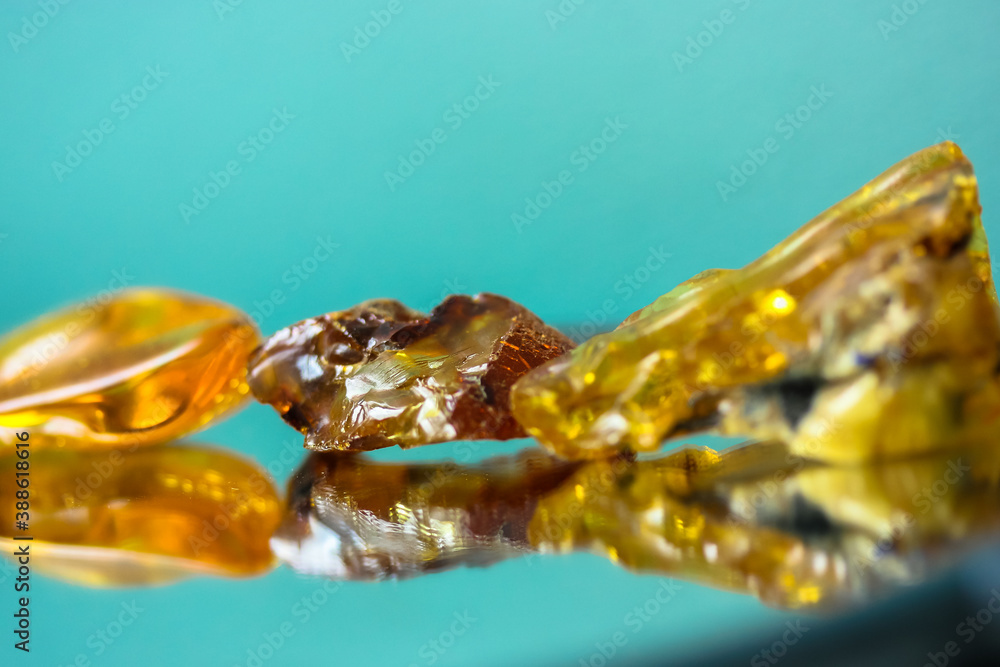 A piece of natural amber on a mirror surface, a reflection of a yellow semi-precious stone A piece of natural amber on a mirror surface, a reflection of a yellow semi-precious stone