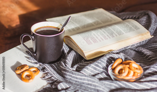 Tableau sur toile Hot steaming coffee in a black Cup, cookies and an old book on a white wooden ta