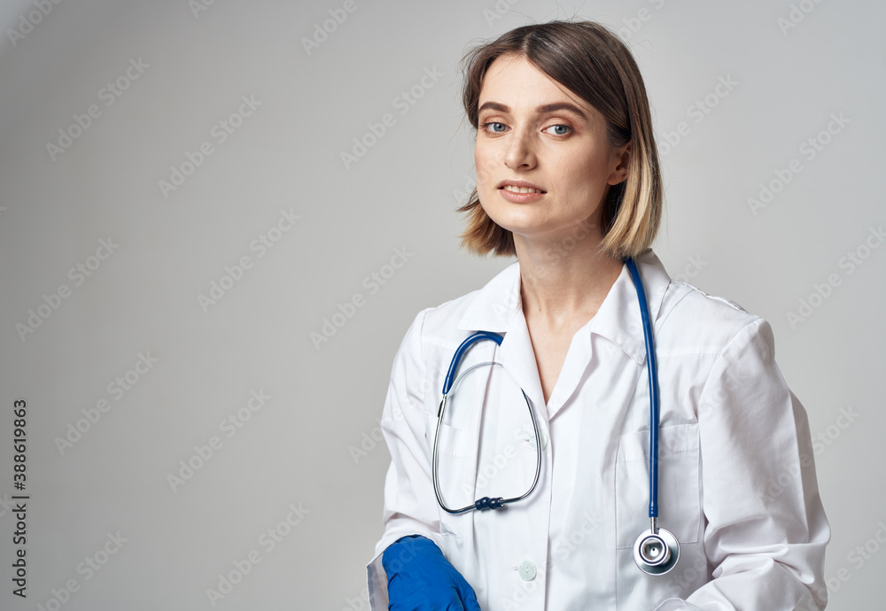 portrait of a nurse in gloves and a medical gown on a light background portrait of a nurse in gloves and a medical gown on a light background