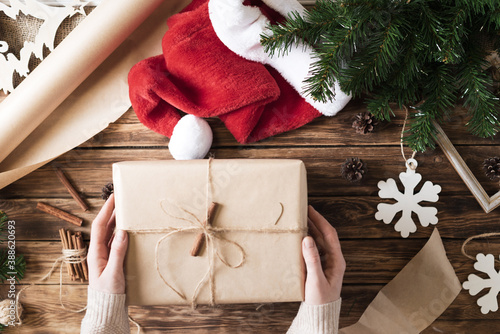 DIY Christmas gifts and packaging of kraft paper on a wooden table. The process of making gifts in a rustic style for the New Year.