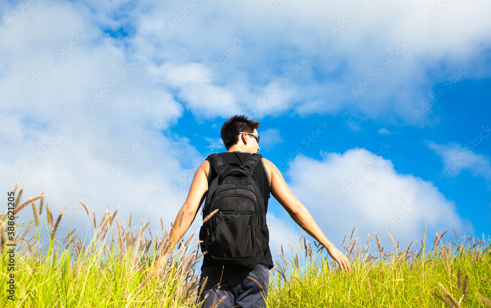 Male traveler hiking walking through a grass field. Male traveler hiking walking through a grass field.
