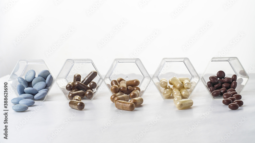 Medical capsules spilled out of a glass hexagonal jars Medical capsules spilled out of a glass hexagonal jars