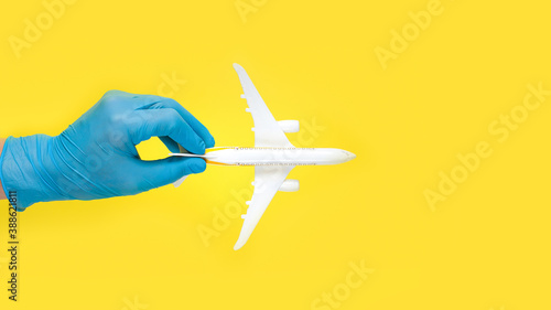 Hand in glove holding model airplanes on yellow background. Concept traveling. Copy space