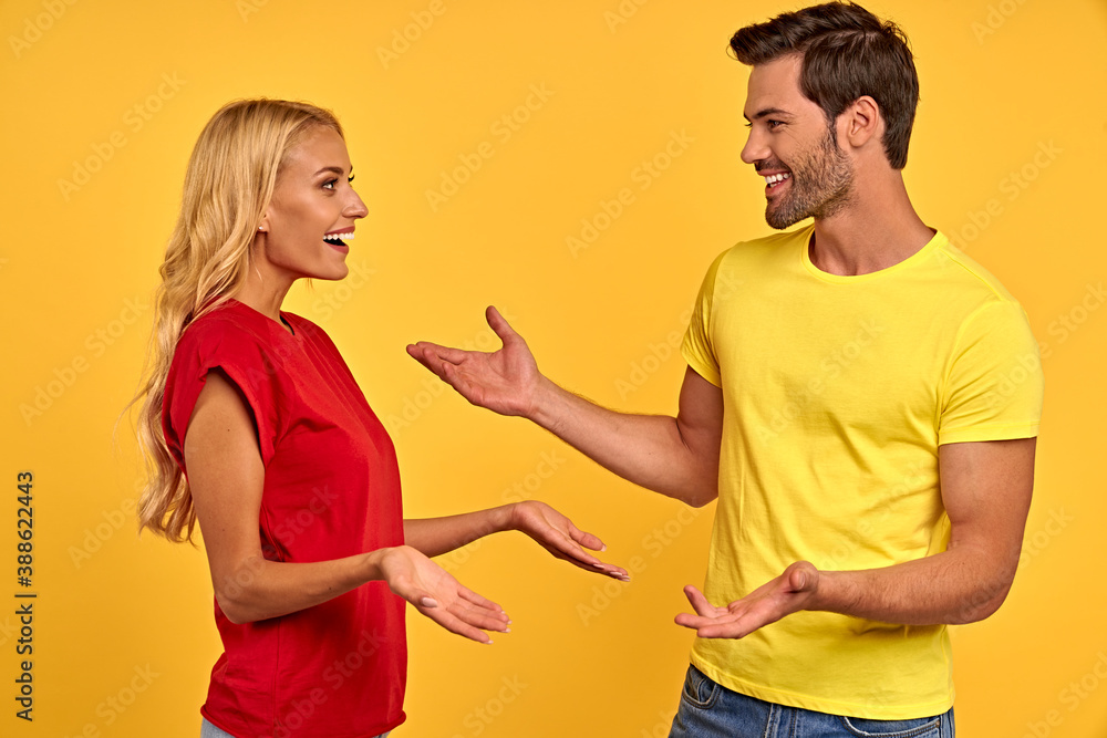 Side view of cheerful young couple two friends guy girl in casual clothes posing isolated on yellow background. People lifestyle concept. Mock up copy space. Looking at each other, speaking talking Side view of cheerful young couple two friends guy girl in casual clothes posing isolated on yellow background. People lifestyle concept. Mock up copy space. Looking at each other, speaking talking