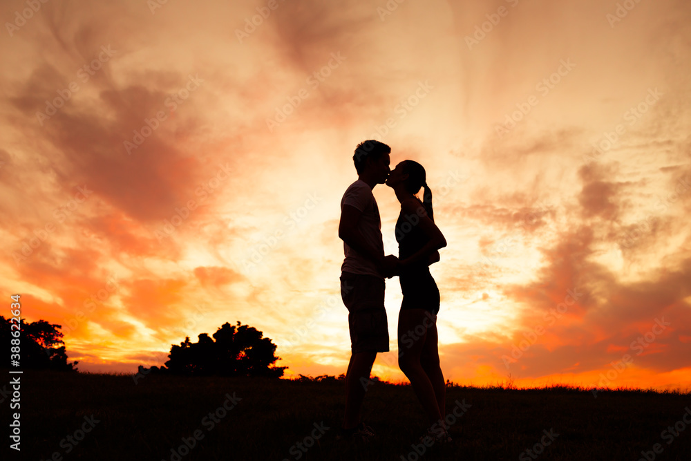 Young couple silhouette in love kissing at sunset. 