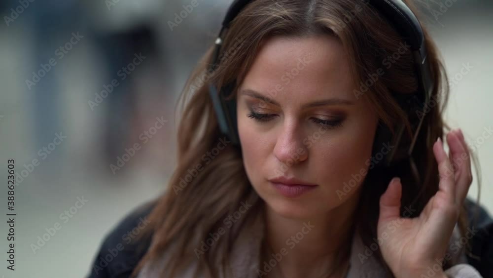 woman is enjoying favorite music in headphones and hot coffee or tea in cafeteria, sitting on open terrace woman is enjoying favorite music in headphones and hot coffee or tea in cafeteria, sitting on open terrace