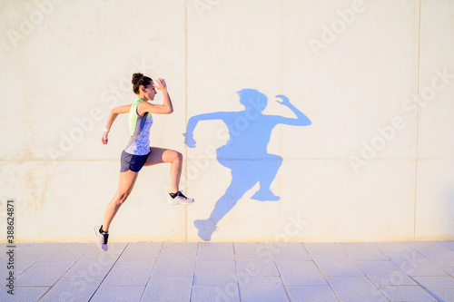 woman jumping next to wall and shadow reflection