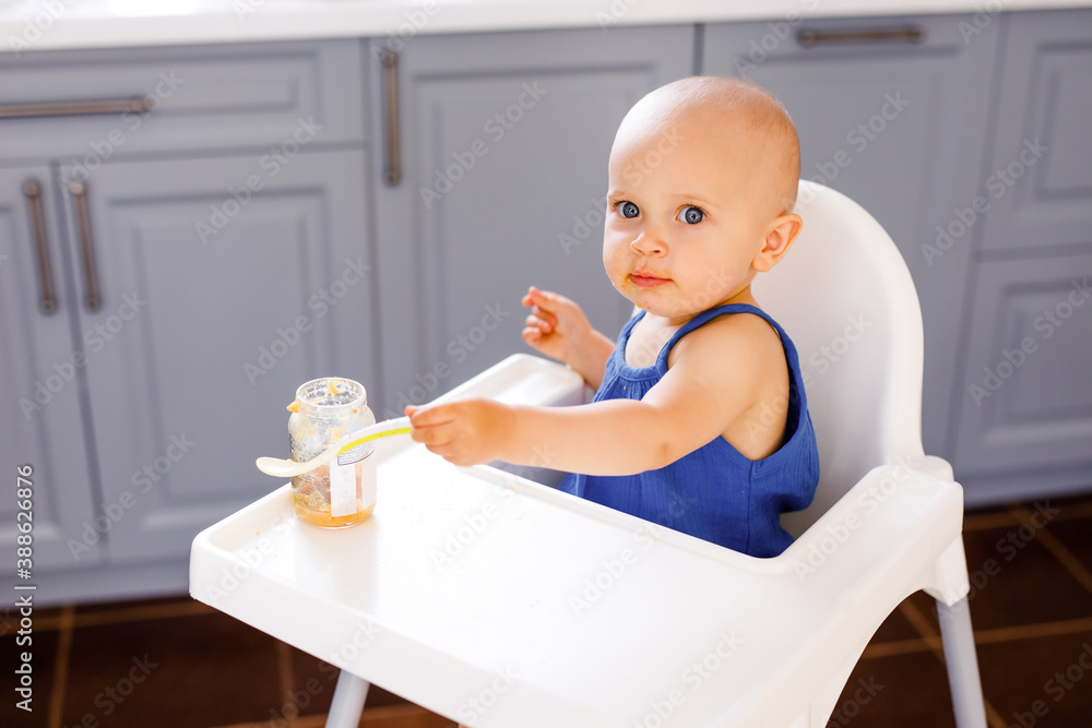 baby girl sitting in a child's chair eating fruit on a white background. baby food concept, space for text baby girl sitting in a child's chair eating fruit on a white background. baby food concept, space for text