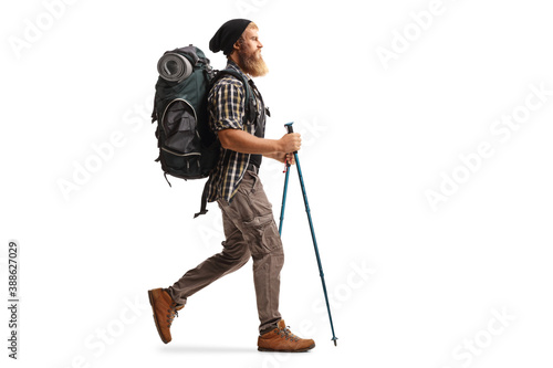 Fototapeta Full length profile shot of a bearded man with a backpack and hiking poles walki
