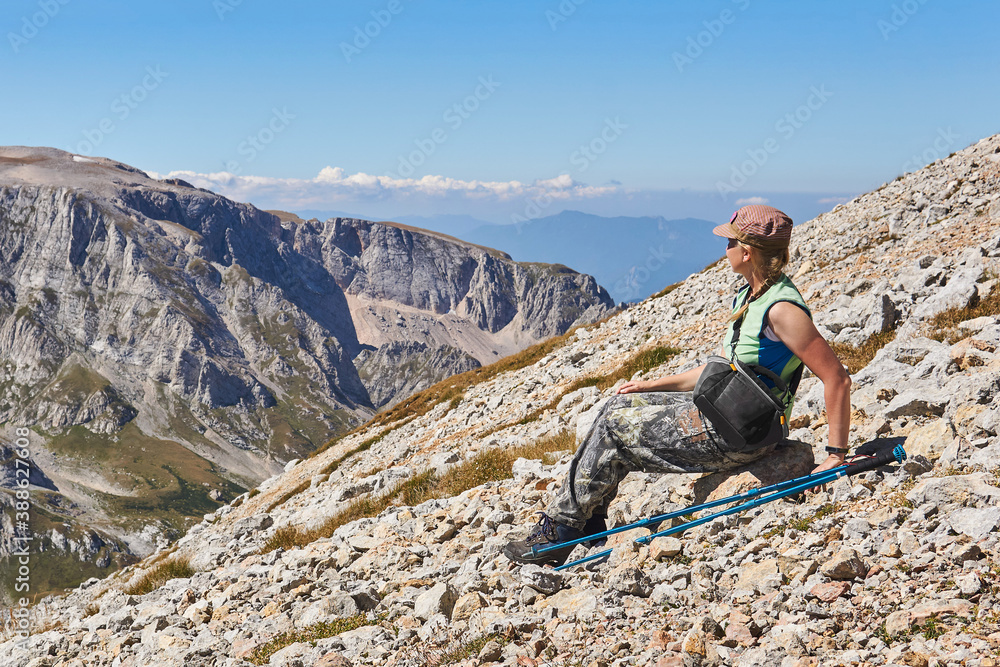 woman traveler resting on a high mountain slope admiring the landscape