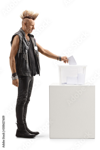 Full length profile shot of a punk with a mohawk putting a vote in an election box photo