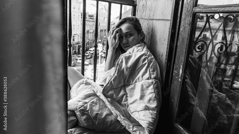 happy young girl. Morning sunrise girl sitting on the balcony wrapped in a bright blanket, nice morning. Selective focus. Black and white photo 