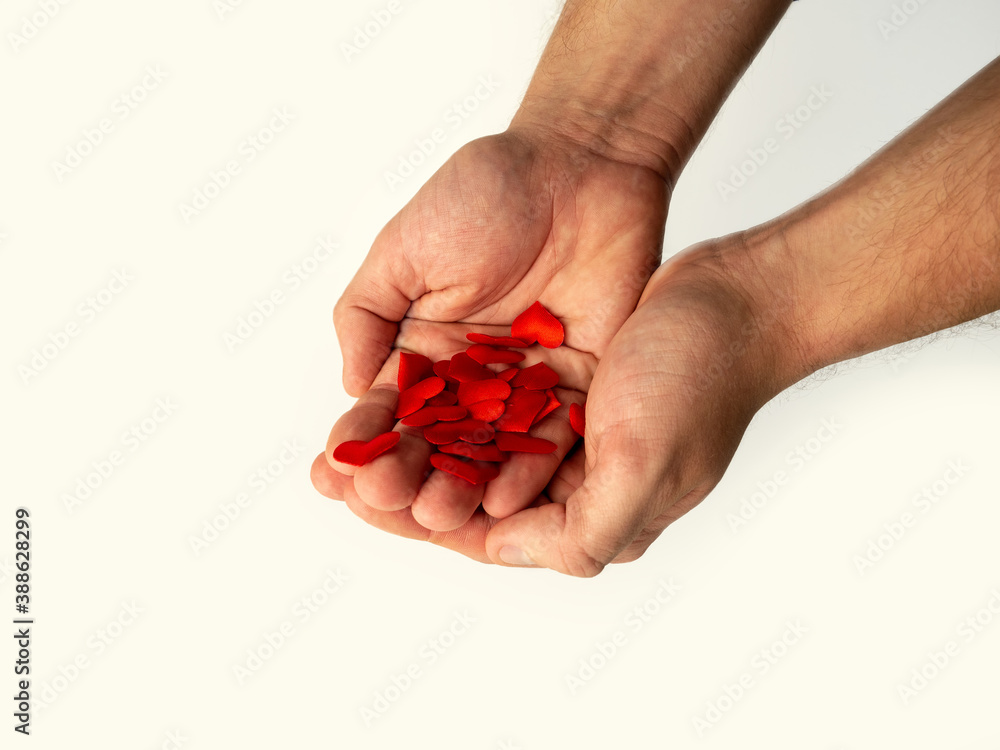 A man's hands hold small hearts on a white isolated background. The concept of love, tenderness, Valentine's day A man's hands hold small hearts on a white isolated background. The concept of love, tenderness, Valentine's day